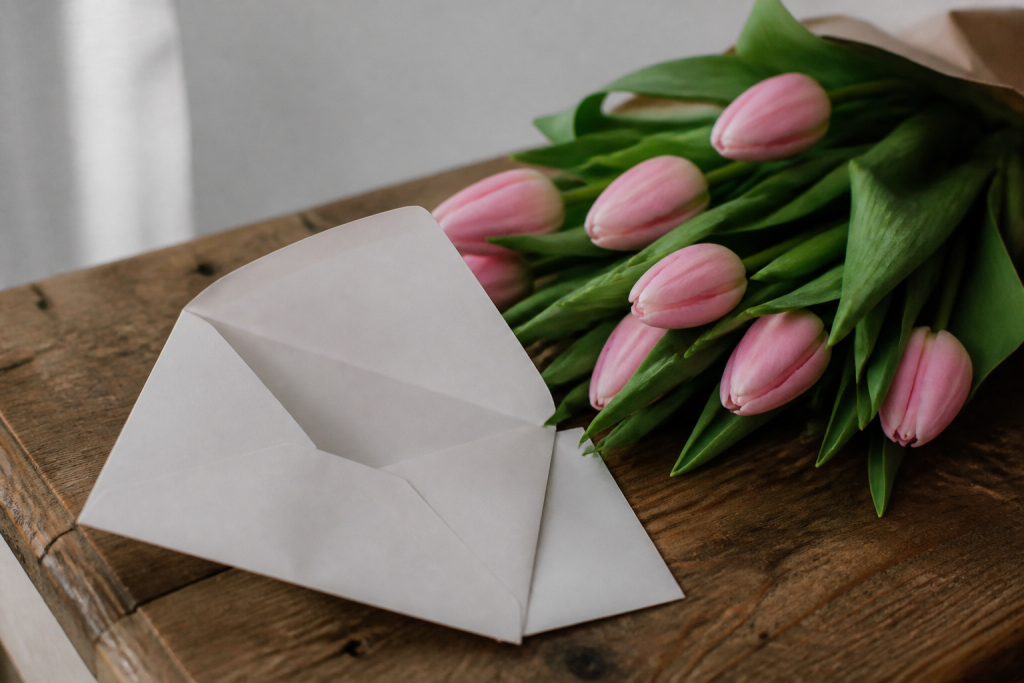 Enveloppe blanche ouverte a cote de tulipes roses