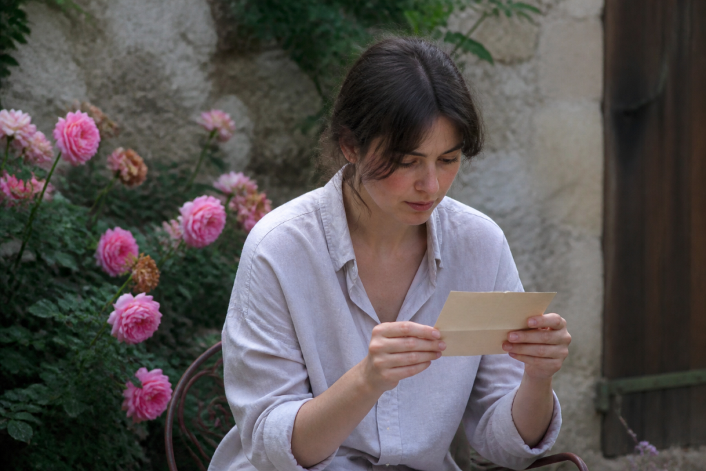 Femme lisant une lettre manuscrite entre roses
