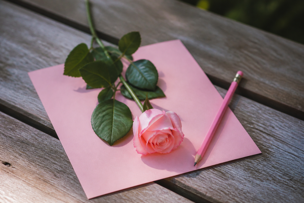 Lettre manuscrite rose avec fleur et crayon
